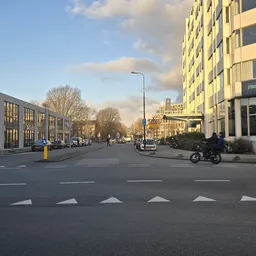 Straatgevel aan De Bruyn Kopsstraat met gele winkelgebouw en 'First Class Sports' winkel aan rechterkant