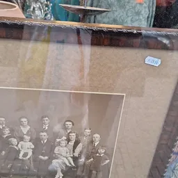 Ingelijste zwart-witfoto van een groepsportret uit vroeger tijd achter glas