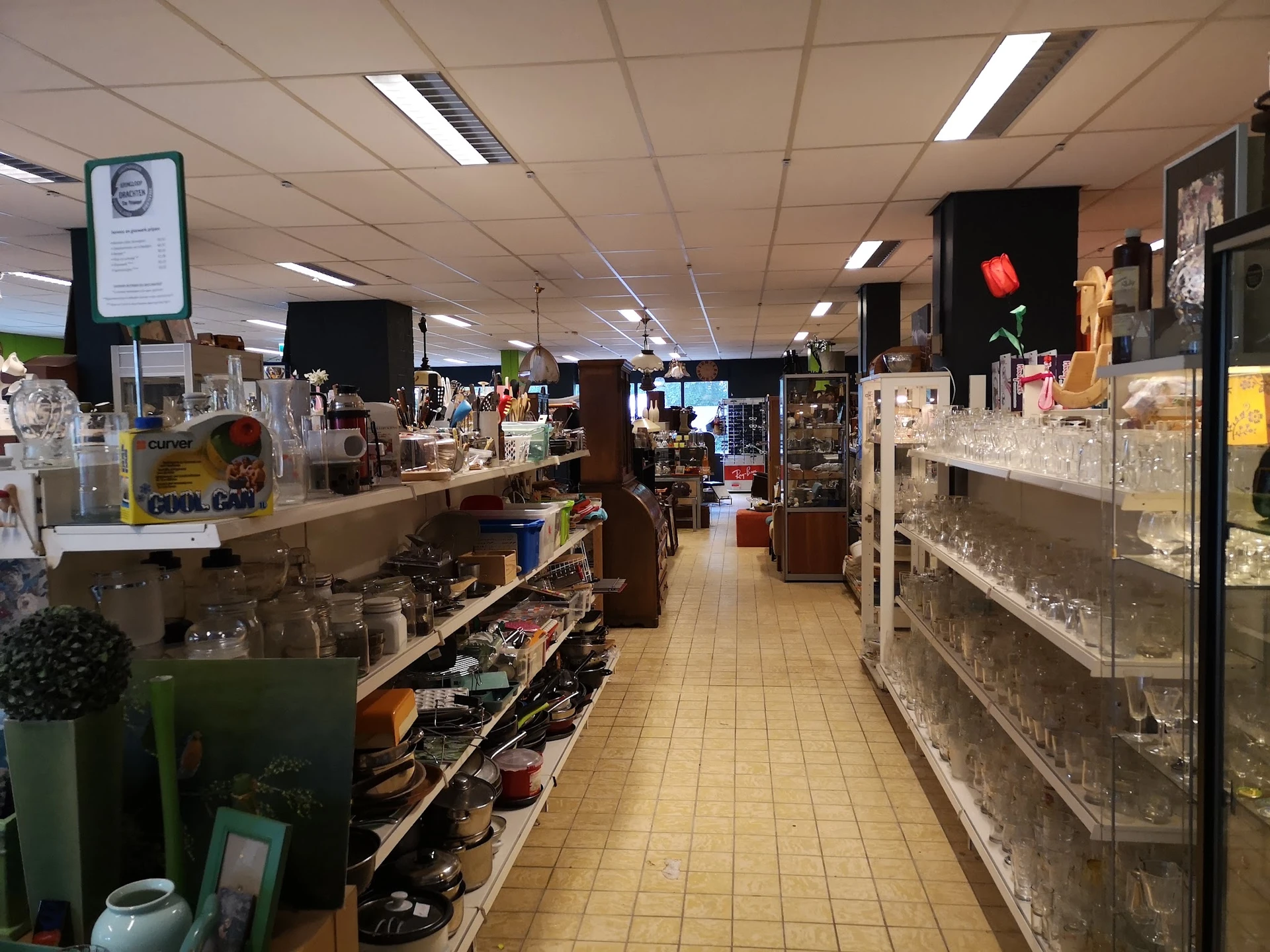 Winkelvloer van kringloopwinkel met stellingen, toonbanken en uiteenlopende tweedehands spullen