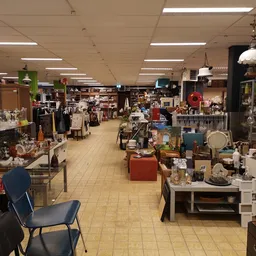 Ruime winkelvloer van kringloopwinkel met diverse stellingen, meubels en huishoudelijke artikelen uitgestald