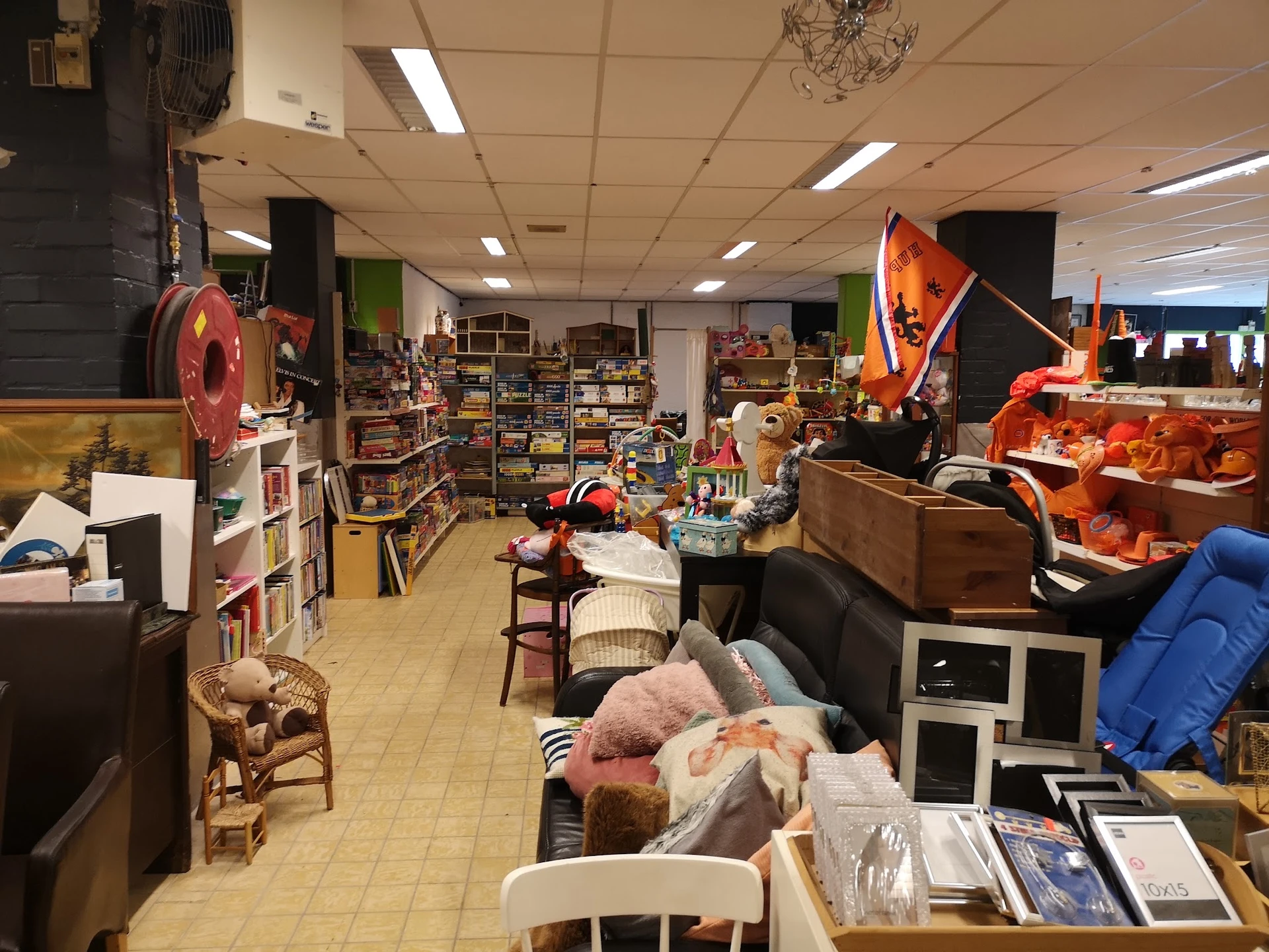 Binnenaanzicht van kringloopwinkel met meubels, huishoudartikelen en verschillende spullen op stellingen