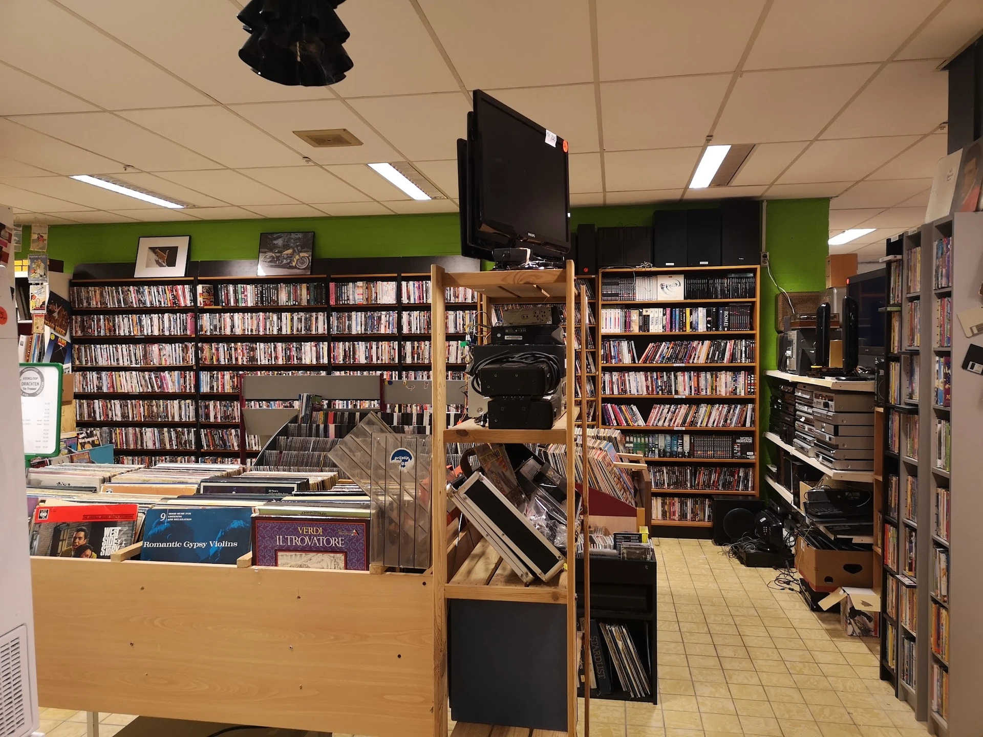 Winkelvloer met cd- en dvd-rekken, boekenkastjes en uitgestalde media in een kringloopwinkel