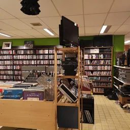 Winkelvloer met cd- en dvd-rekken, boekenkastjes en uitgestalde media in een kringloopwinkel