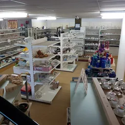 Overzicht van de kringloopwinkel met vitrines, stellingen en verschillende afdelingen met huishoudelijke artikelen en decorat