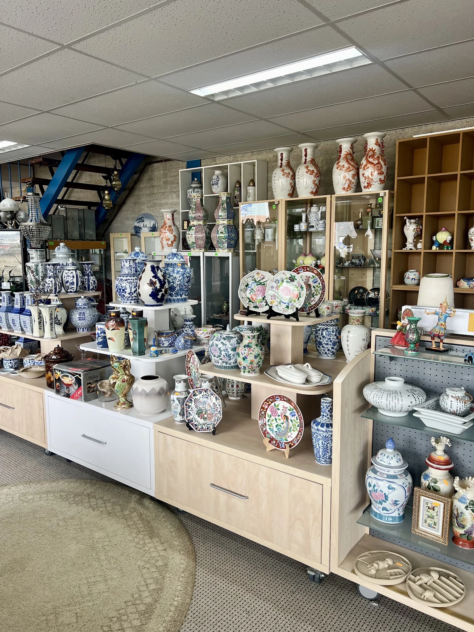 Uitstallingen met blauw-wit porselein, decoratieve borden, vazen en aardewerk in winkelrekken