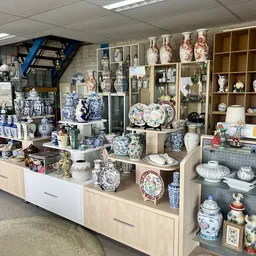 Uitstallingen met blauw-wit porselein, decoratieve borden, vazen en aardewerk in winkelrekken