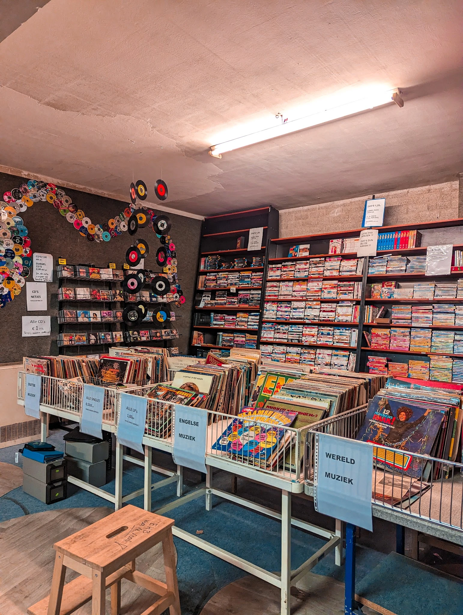 Uitgestalde cd's, vinyl en dvd's in bakken en op schappen in een kringloopwinkel
