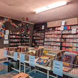 Uitgestalde cd's, vinyl en dvd's in bakken en op schappen in een kringloopwinkel