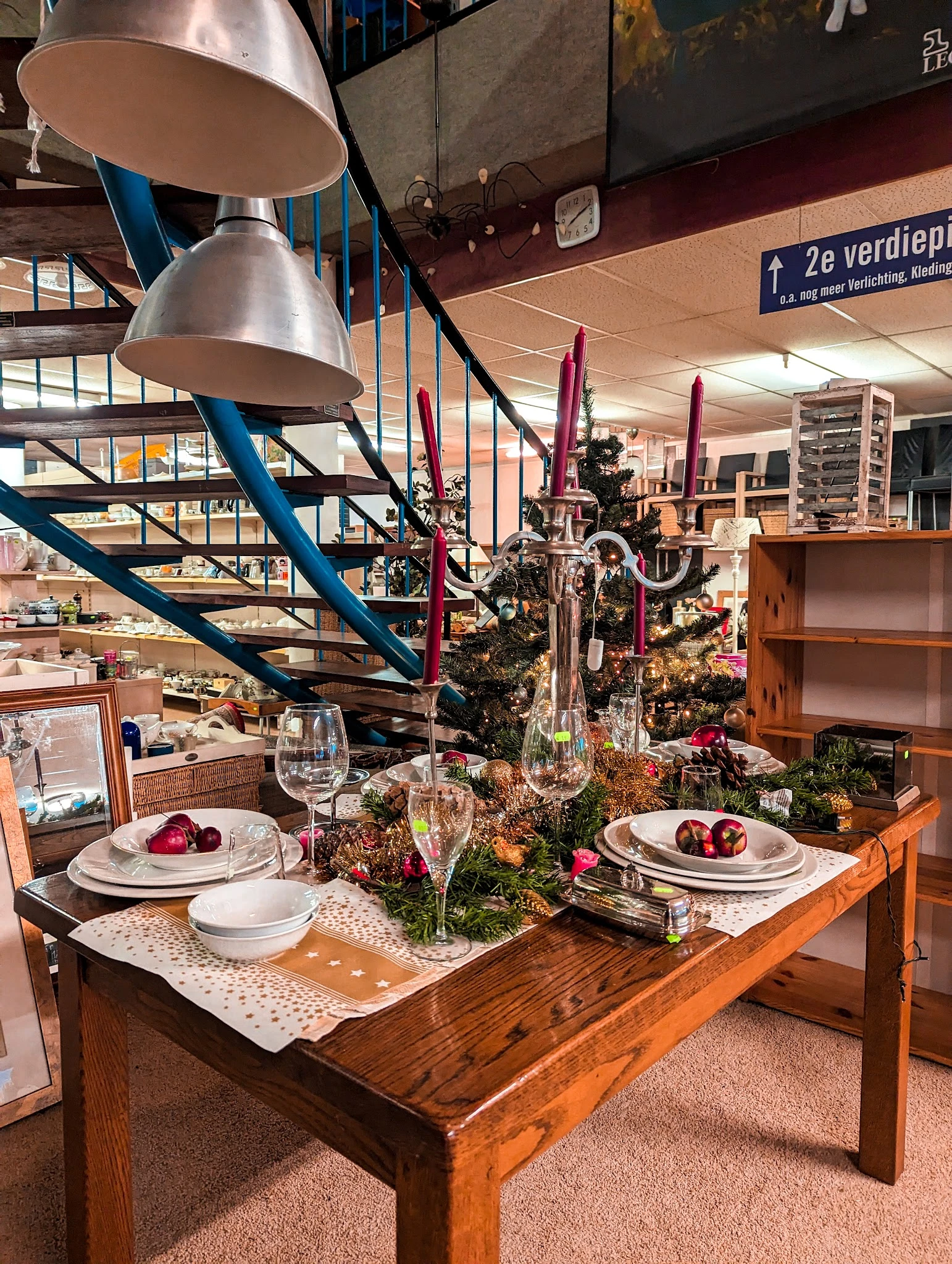 Gedekte tafel met servies, glazen en kaarsen tussen groene planten en decoraties