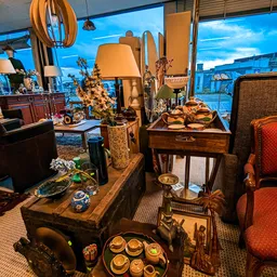 Interieur met uitgestalde meubels en decoratieve artikelen: lampen, stoelen, tafels en accessoires in vintage/klassieke stijl