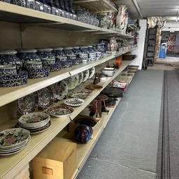 Stellingen met serviesgoed, borden, schalen en aardewerk in verschillende kleuren en patronen