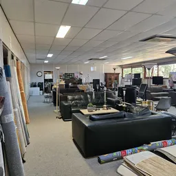 Winkelvloer met zwarte banken, meubels en diverse tweedehands spullen onder fluorescente verlichting