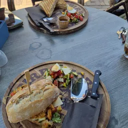 Bord met broodje en groentesalade op houten tafel met bestek en glas water