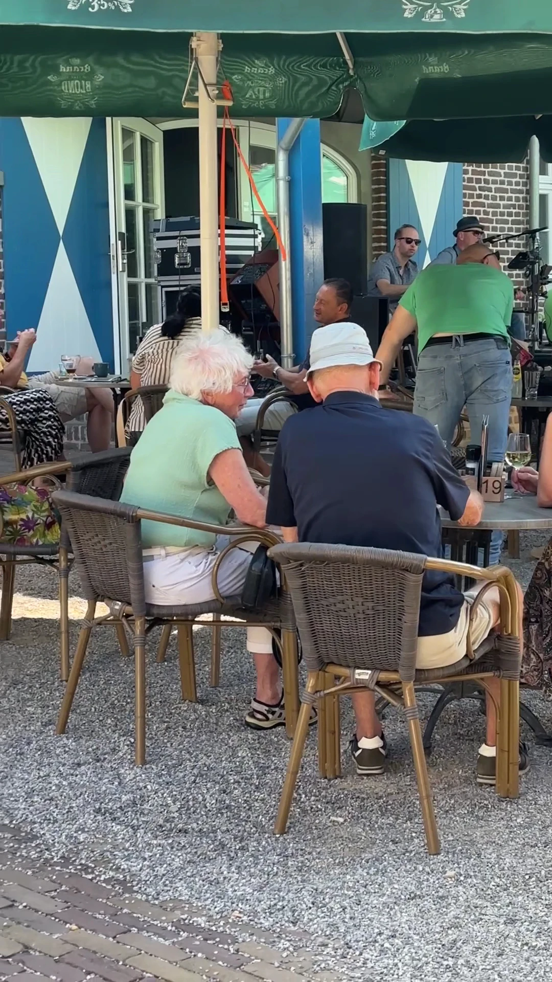 Bezoekers zitten aan tafels op een terras bij de winkel