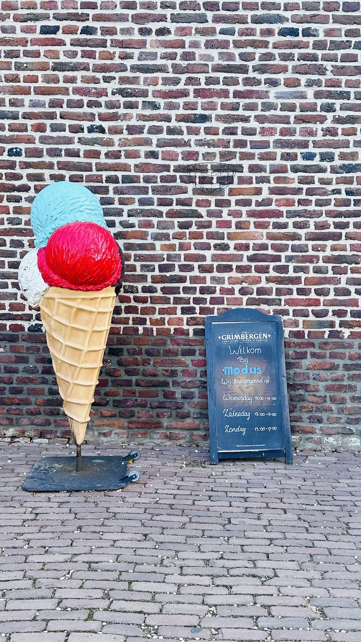 Gevel van bakstenen muur met decoratieve ijshoorn en bord met openingstijden