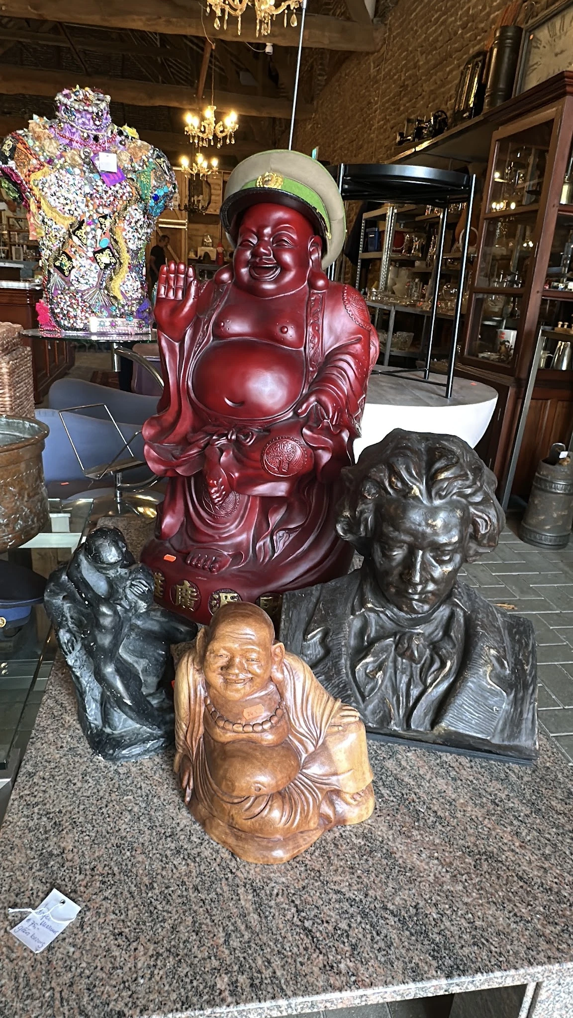 Verzameling beelden en sculpturen: rode Boeddha-buste, houten en bronzen portretten.