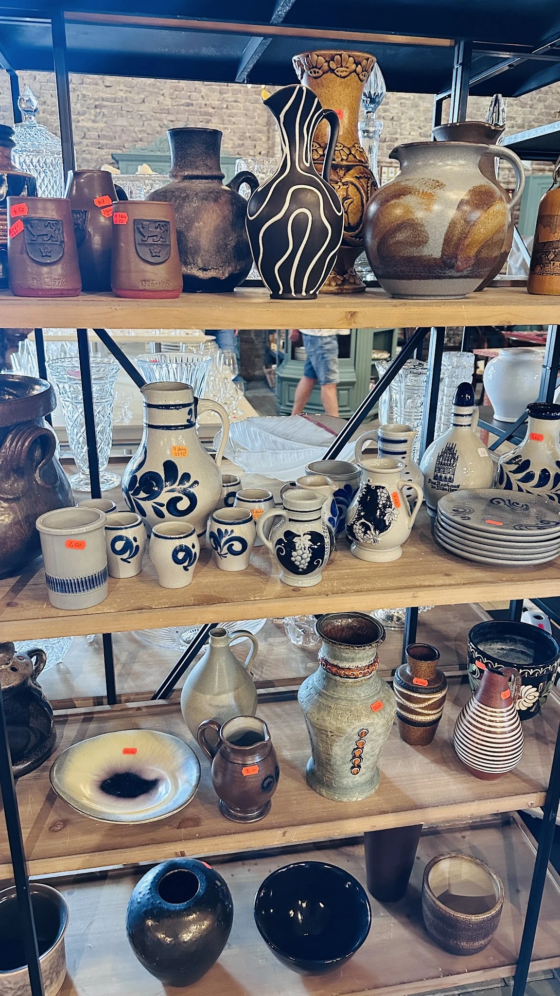 Uitstalling van blauw-wit beschilderd serviesgoed en aardewerk op een houten plank in de winkel