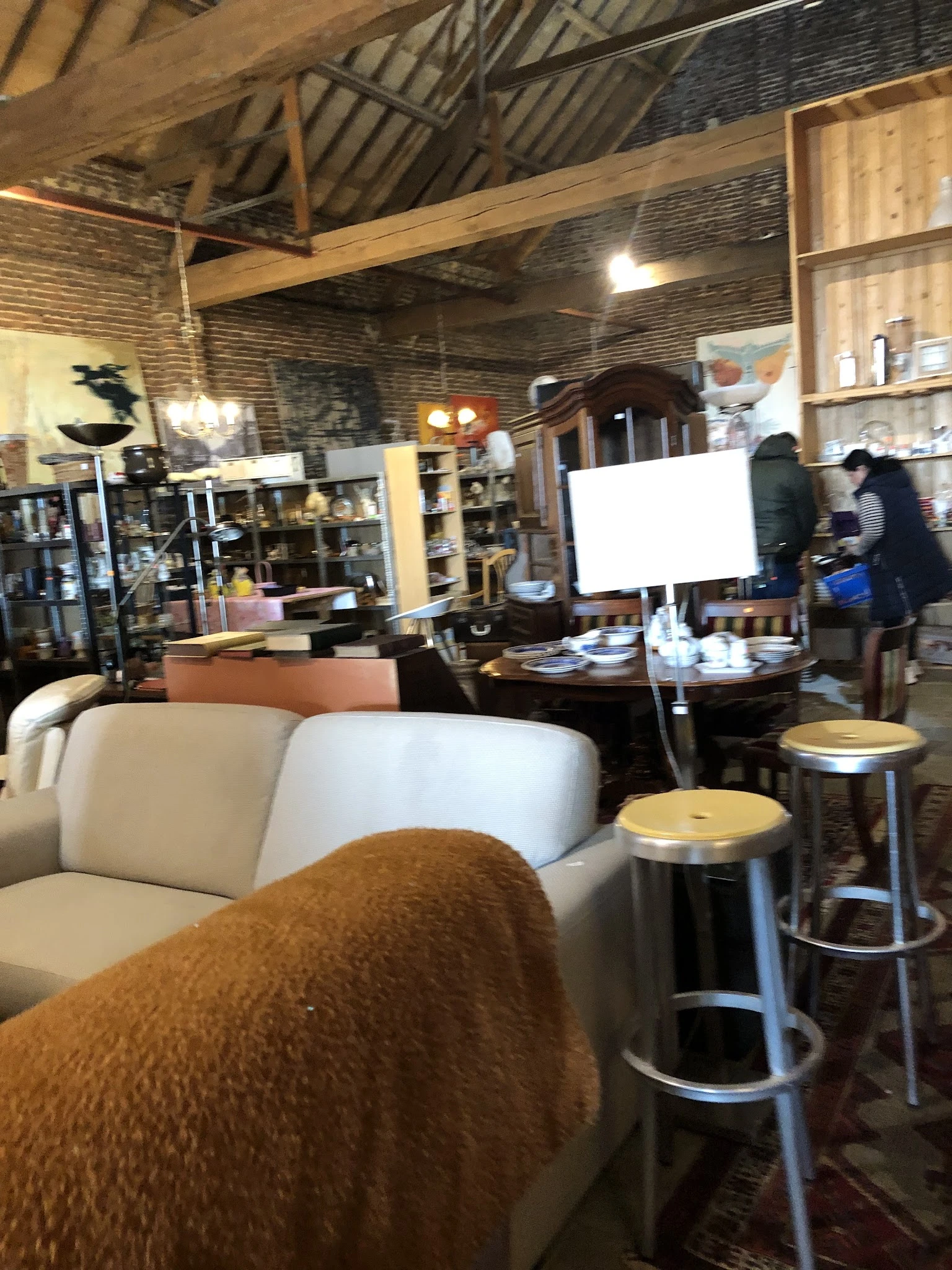 Winkelbinnenruimte met witte fauteuils, tafels, stellingen met spullen en een wit whiteboard op de achtergrond