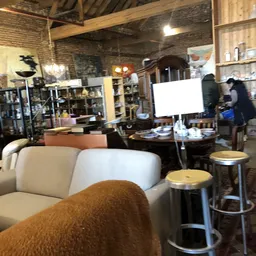 Winkelbinnenruimte met witte fauteuils, tafels, stellingen met spullen en een wit whiteboard op de achtergrond