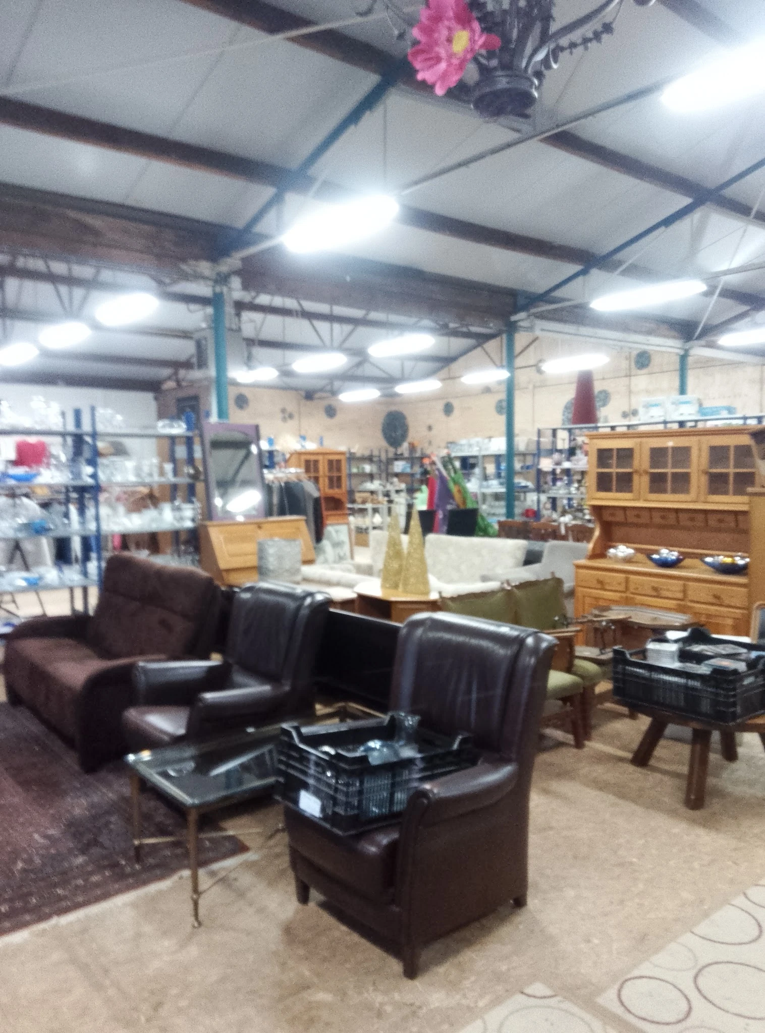 Winkelvloer met bruine leren fauteuils, houten kasten en diverse meubels en huishoudartikelen