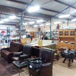 Winkelvloer met bruine leren fauteuils, houten kasten en diverse meubels en huishoudartikelen