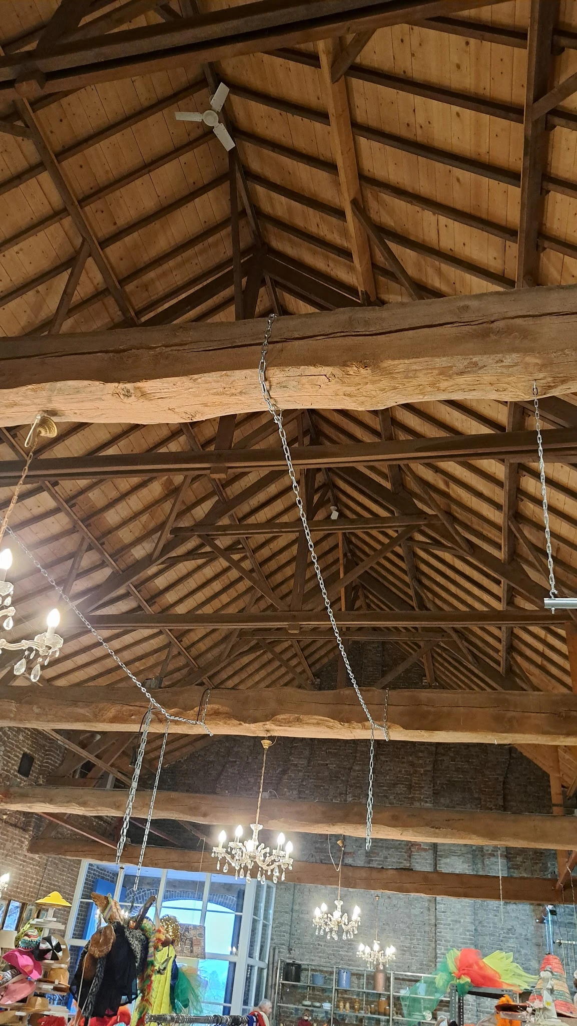 Houten dakconstructie met balken en hangende kettingen in een schuur of boerderijgebouw