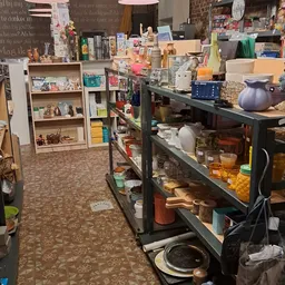 Winkelvloer met stellingen vol huishoudartikelen, glazen potten, servies en diverse spullen