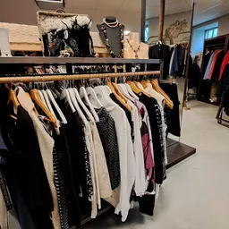 Kledingrekken met tweedehands dames- en herenkleding in verschillende kleuren en maten