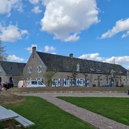 Voorkant van stenen kringloopwinkel aan Naborchweg met ingang en blauwe decoratie