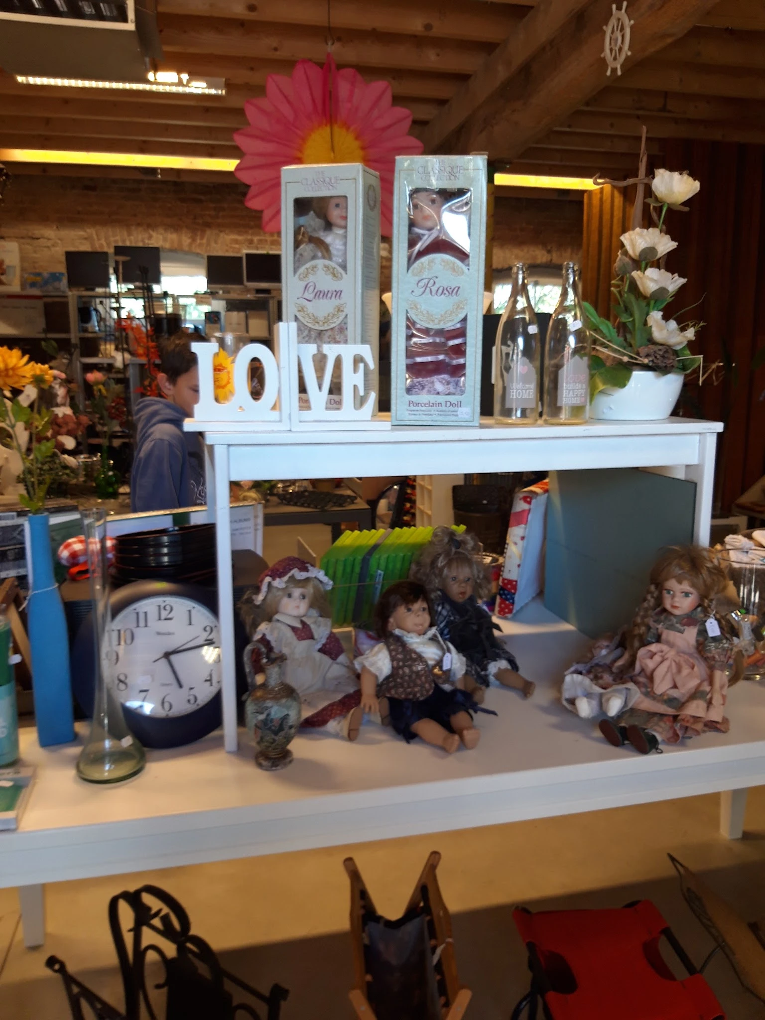 Vitrinekast met verzameling poppen, klok, bloemen en decoratieve items