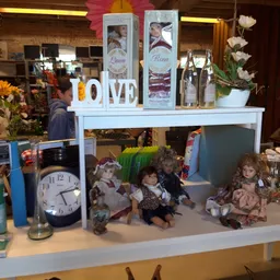 Vitrinekast met verzameling poppen, klok, bloemen en decoratieve items