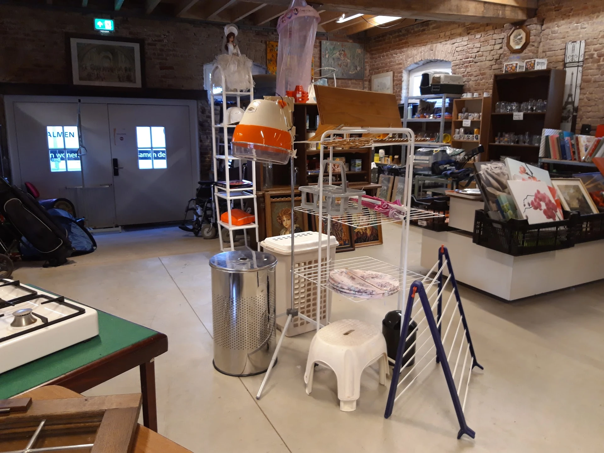 Winkelvloer met diverse gebruiksartikelen, stellingen en huisraad in een kringloopwinkel