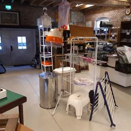 Winkelvloer met diverse gebruiksartikelen, stellingen en huisraad in een kringloopwinkel