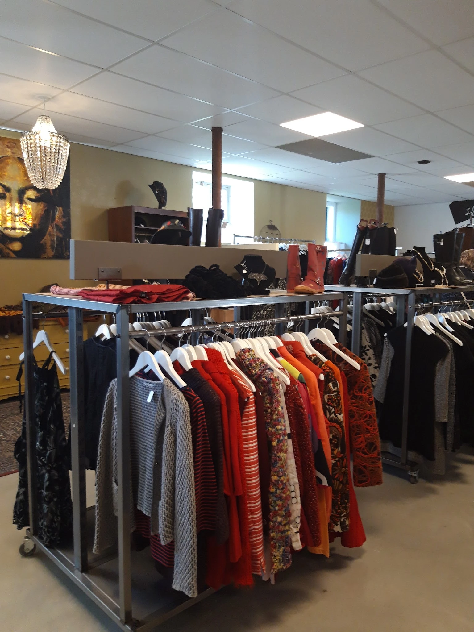 Rekken met tweedehands dameskleding in verschillende kleuren, vooral rode en gekleurde items op hangers uitgestald