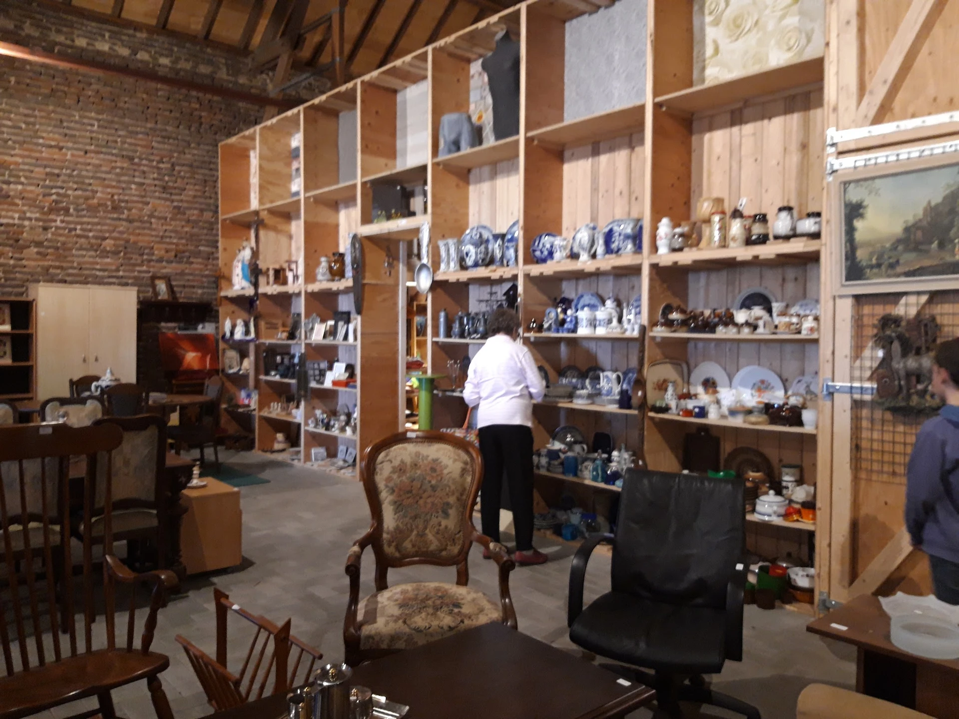 Winkelinterieur met grote houten stellingkasten vol met blauw serviesgoed en decoraties