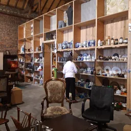 Winkelinterieur met grote houten stellingkasten vol met blauw serviesgoed en decoraties