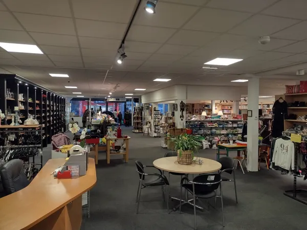 Winkelvloer van kringloopwinkel met stellingen, tafels, stoelen en diverse tweedehands spullen