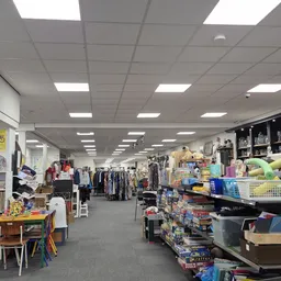 Binnenaanzicht van kringloopwinkel met kledingrekken, stellingen met spullen en diverse artikelen