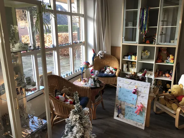 Lichte winkelruimte met rattan meubels, speelgoed, decoratie en uitgangsborden bij grote ramen met uitzicht op tuin