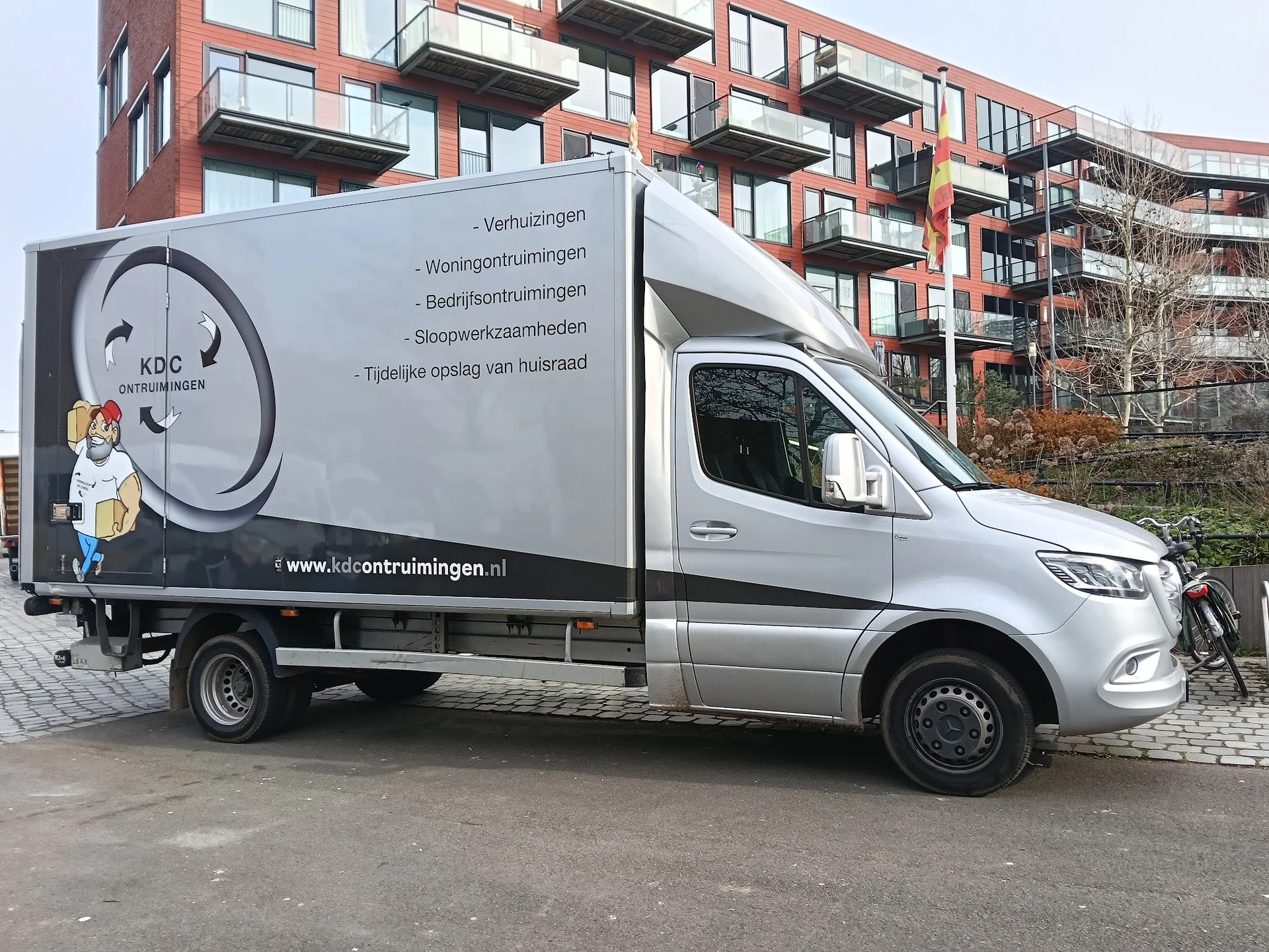 Bedrijfsbus van KDC Ontruimingen met logo en contact gegevens op de zijkant