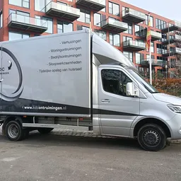 Bedrijfsbus van KDC Ontruimingen met logo en contact gegevens op de zijkant