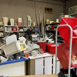 Binnenzicht van kringloopwinkel met stellingen, rode opbergboxen en diverse spullen