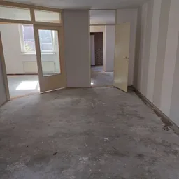 Lege winkelruimte met betonnen vloer, witte muren en open deuren naar andere kamers