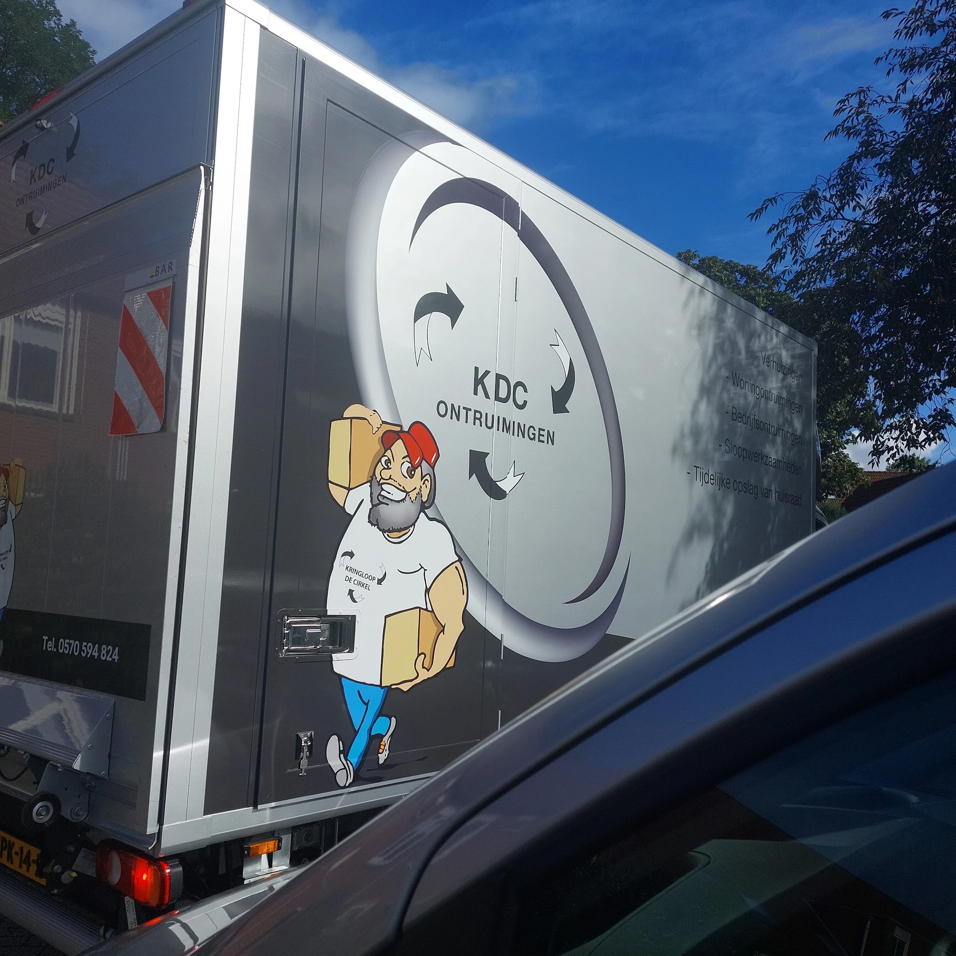 Bestelwagen met KDC Ontruimingen logo en illustratie van pakketbezorger met kartondoos