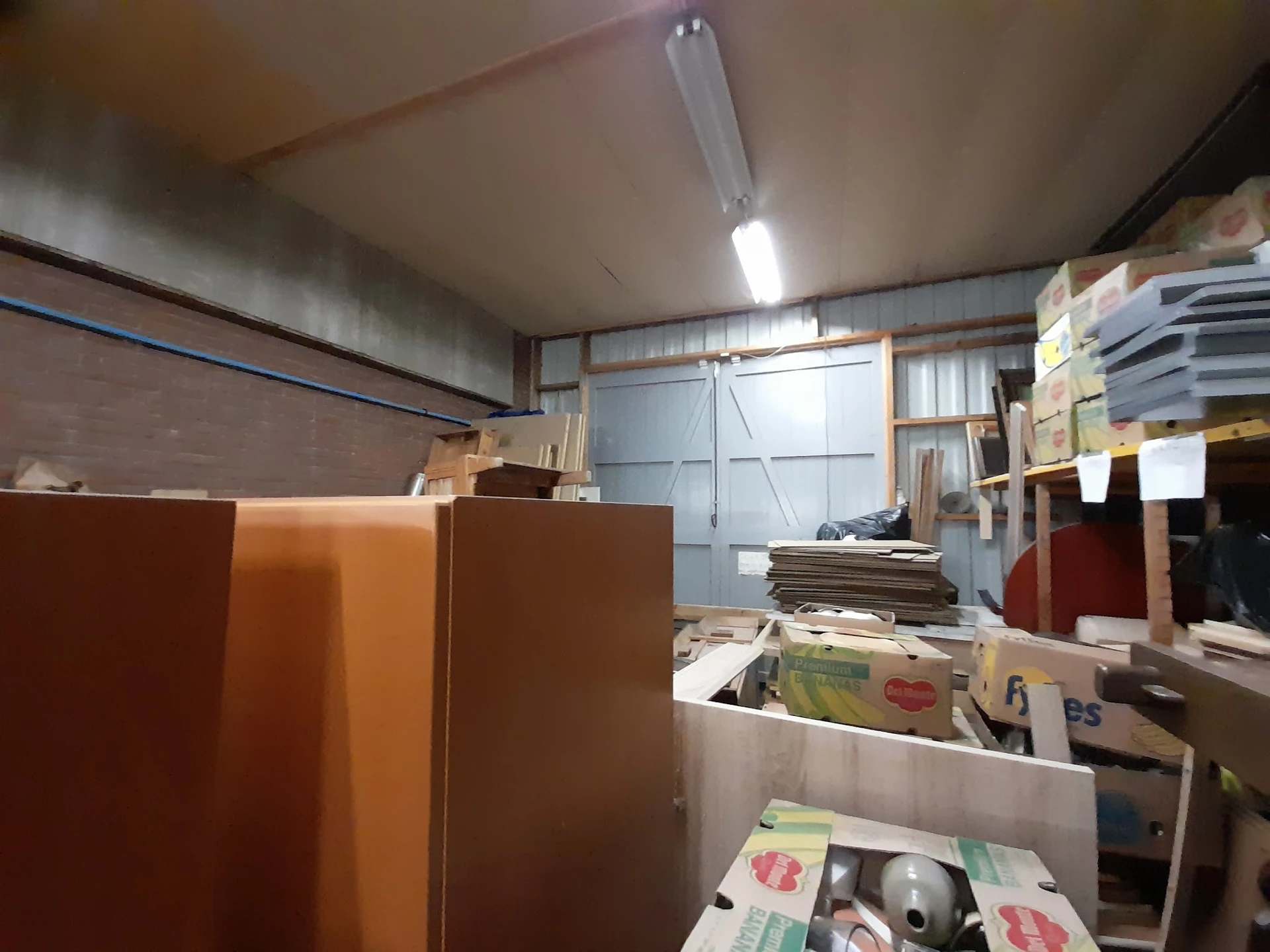 Magazijnruimte met houten panelen, dozen en opgeslagen goederen onder fluorescentie verlichting