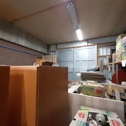 Magazijnruimte met houten panelen, dozen en opgeslagen goederen onder fluorescentie verlichting