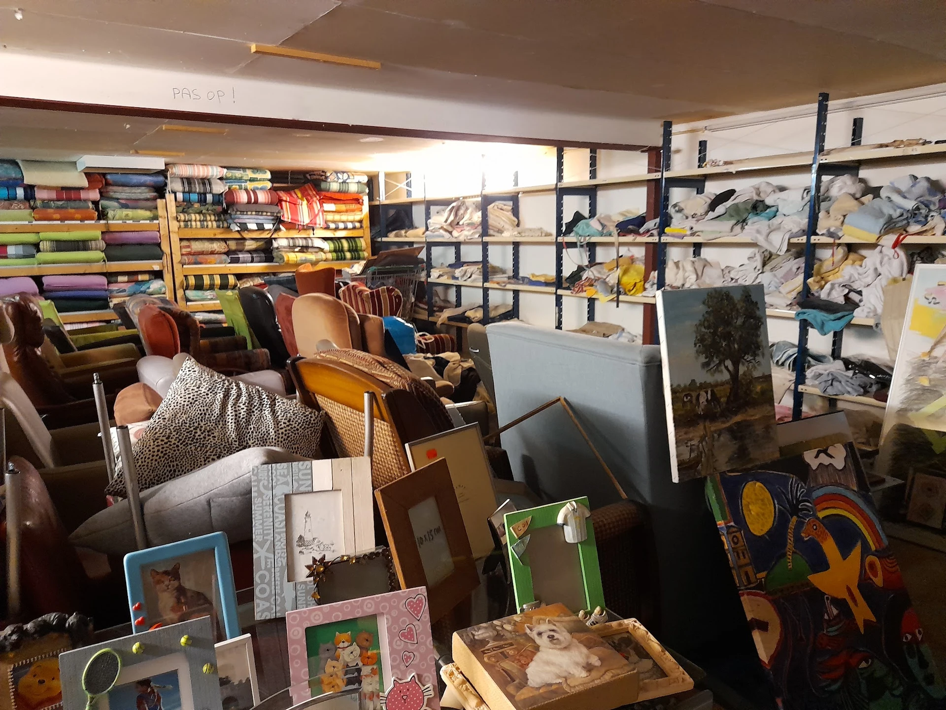 Overzicht van winkelinterieur met stellingen, textiel, kunstwerken en diverse spullen