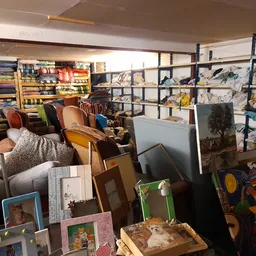 Overzicht van winkelinterieur met stellingen, textiel, kunstwerken en diverse spullen