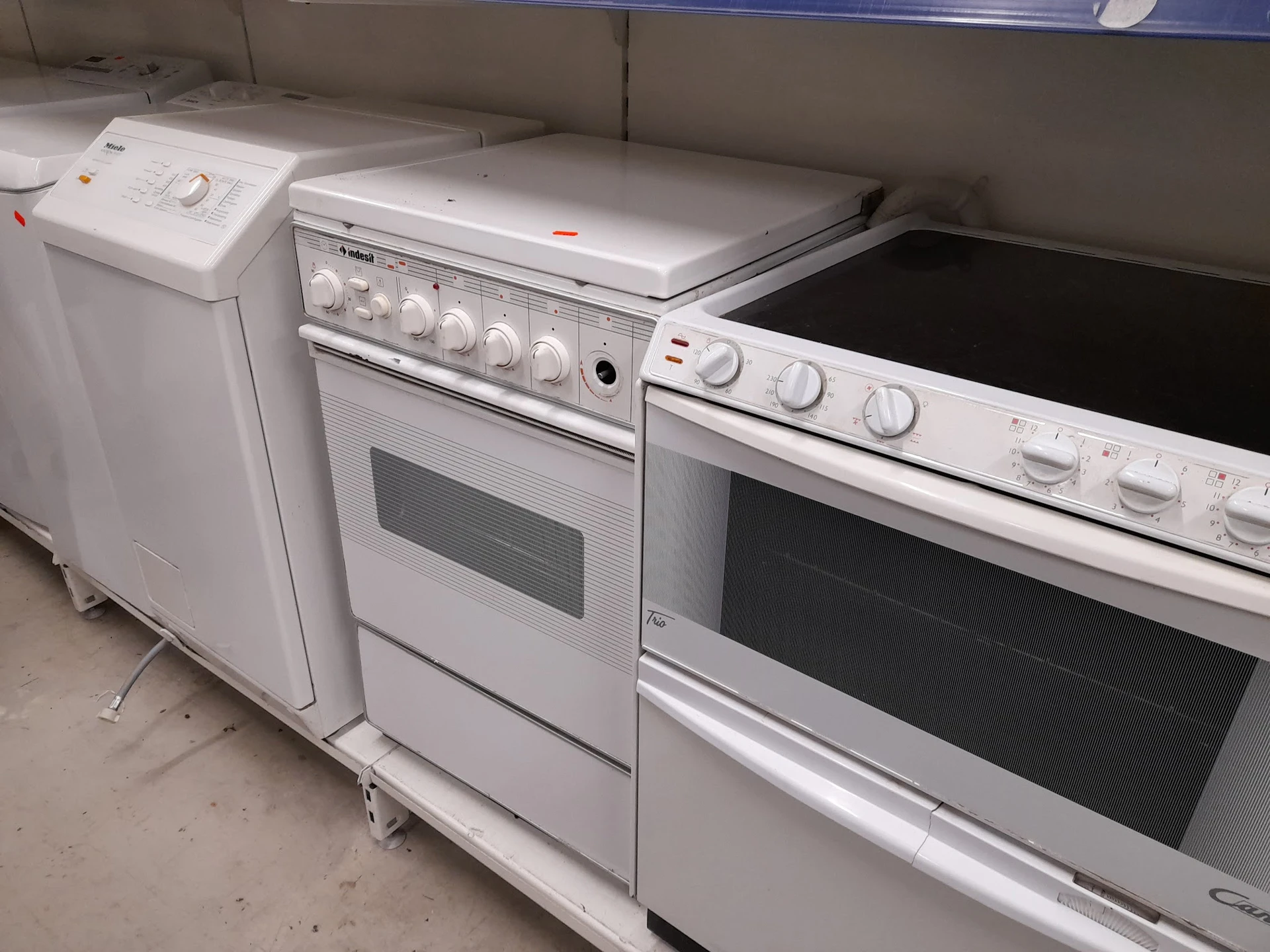Drie witte huishoudapparaten: een wasmachine, een oven en een elektrisch fornuis.