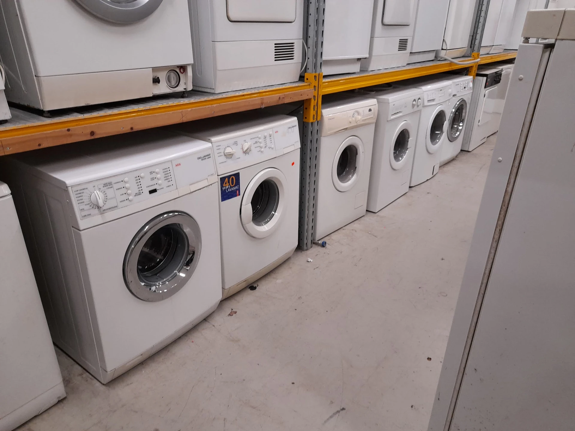 Rij wasmachines in verschillende modellen en kleuren uitgestald in de winkel